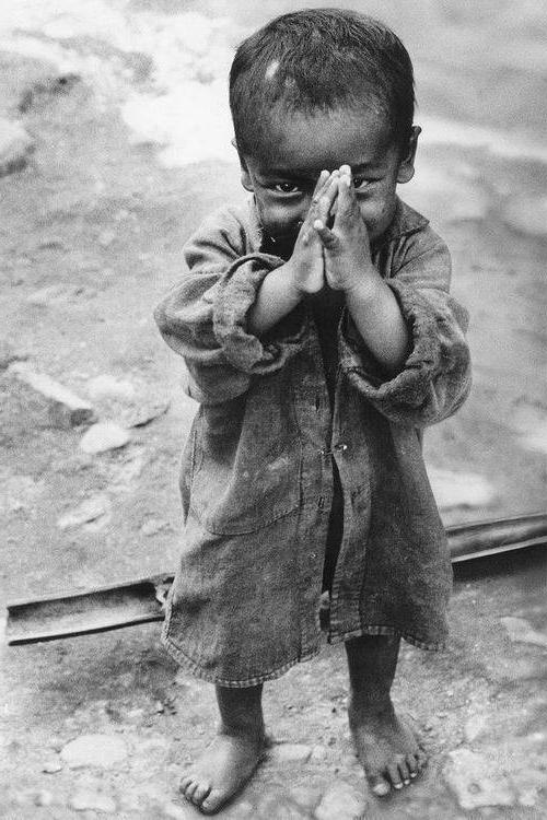 Young child with their hands together in front of their face